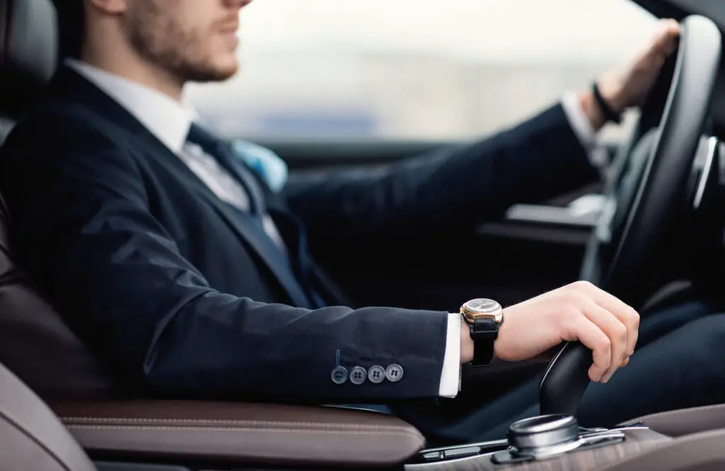 Confident man wearing suit and watch driving car