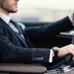 Confident man wearing suit and watch driving car